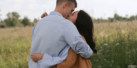 Natural couple embracing in field