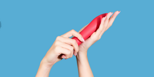 Hands holding up pink vibrator sex toy