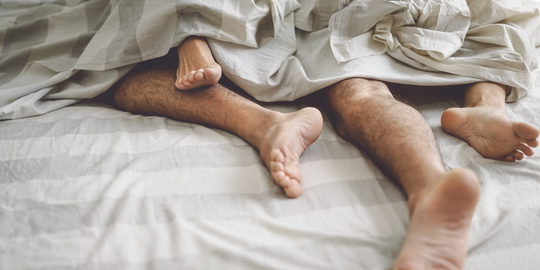 Couples feet poking out of duvet