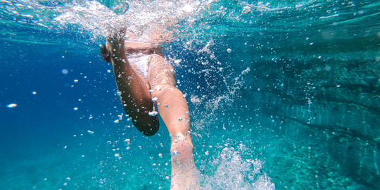 womans legs swimming underwater