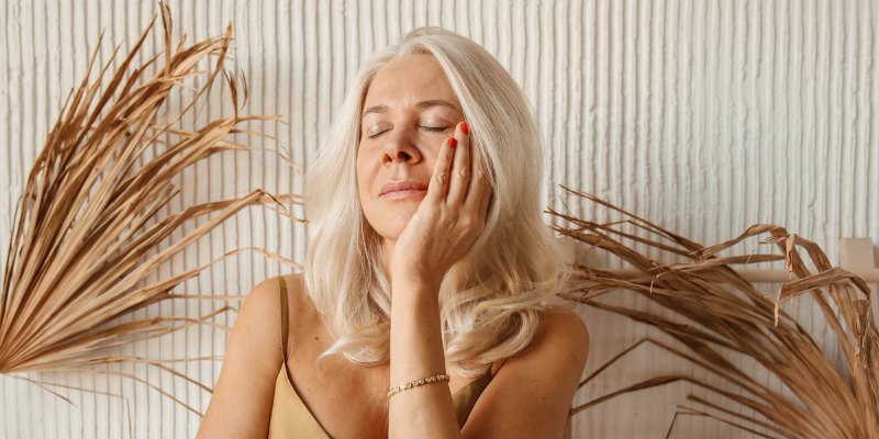 Menopausal women holds head in hand thinking