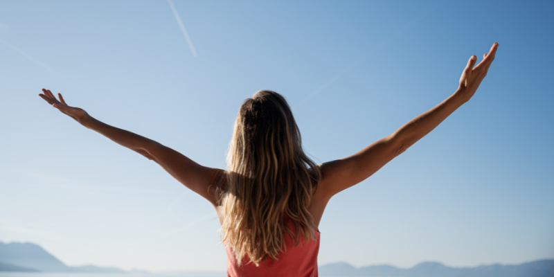 woman holding hands in the air blue sky 