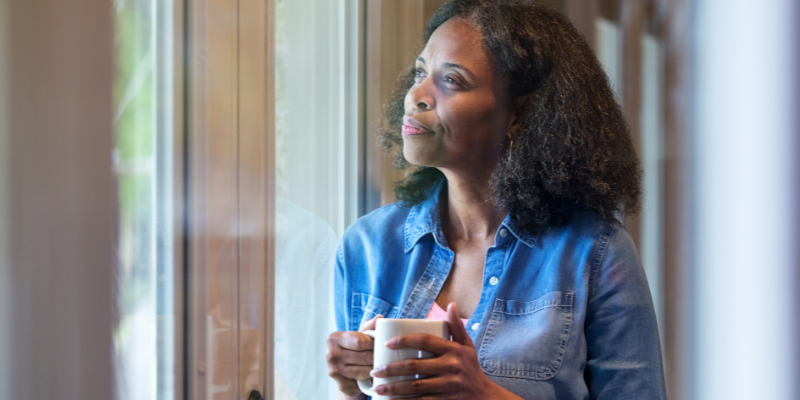 Contemplative women holding mug looking out of window